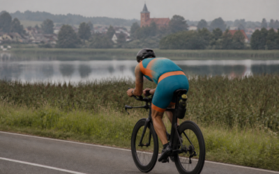 Triathlonista jedzie rower w pozycji aero nad mazurskim jeziorem — rozkład mocy IF i VI