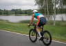 Triathlonista w kolorowym stroju na rowerze nad mazurskim jeziorem