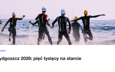 Czterech zawodników w piankach wbiega do morza na starcie