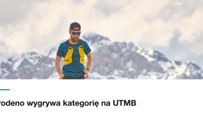 Biegacz górski na skalnym grzbiecie z zaśnieżonymi szczytami w tle