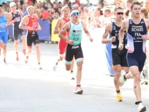 Vasco Vilaça w portugalskim stroju biegnie w grupie zawodników wzdłuż barierek z kibicami
