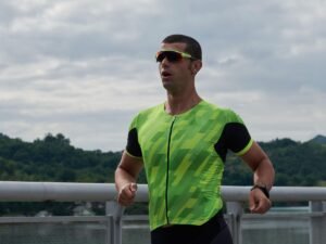 Triathlonista biegnie w stroju startowym po czesci rowerowej