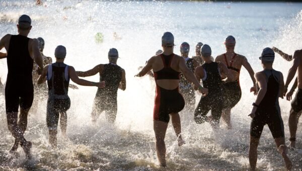 Triathlonisci wbiegajacy do wody na starcie