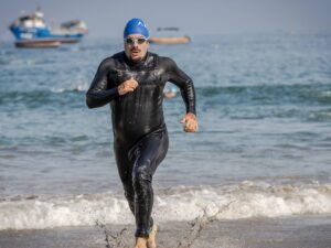 Triathlonisci wybiegajacy z wody w piankach