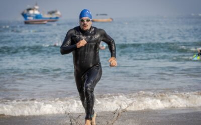 Triathlonisci wybiegajacy z wody w piankach