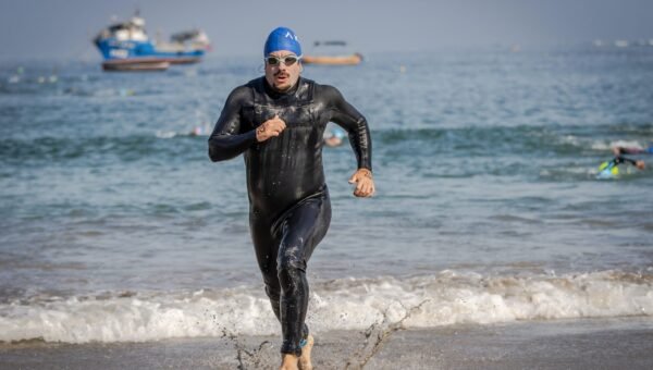 Triathlonisci wybiegajacy z wody w piankach