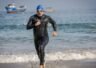 Triathlonisci wybiegajacy z wody w piankach