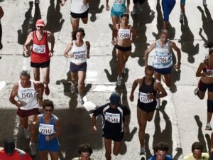 Peleton biegaczy z numerami startowymi na ulicy podczas maratonu