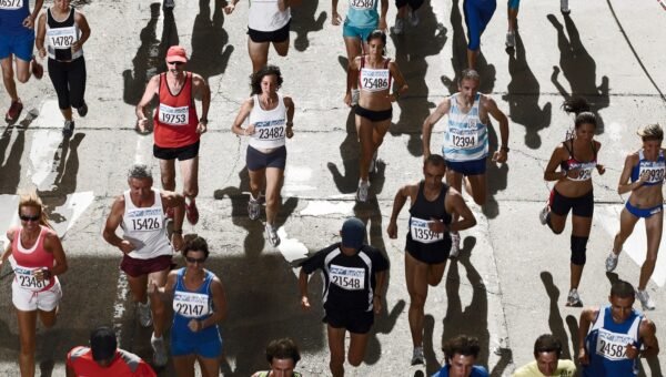 Peleton biegaczy z numerami startowymi na ulicy podczas maratonu