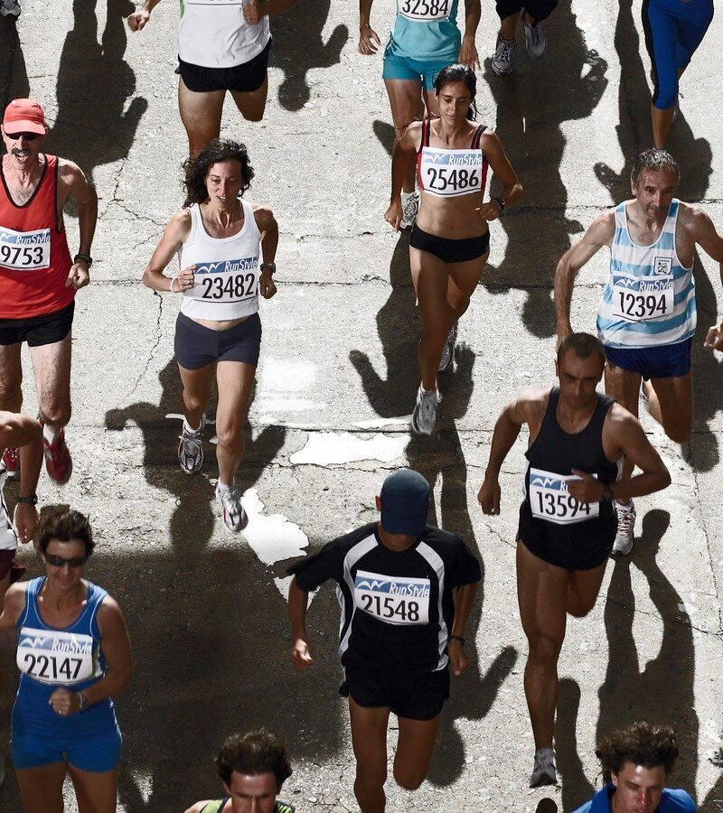 Peleton biegaczy z numerami startowymi na ulicy podczas maratonu