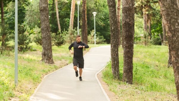 Biegacz sprawdzajacy zegarek sportowy na trasie w parku