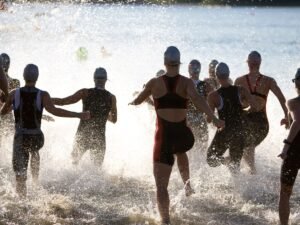 Triathlonisci wbiegajacy do wody na starcie zawodow